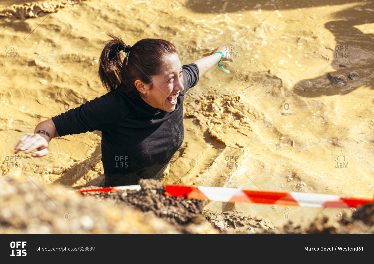 Woman in mud pit in extreme obstacle race