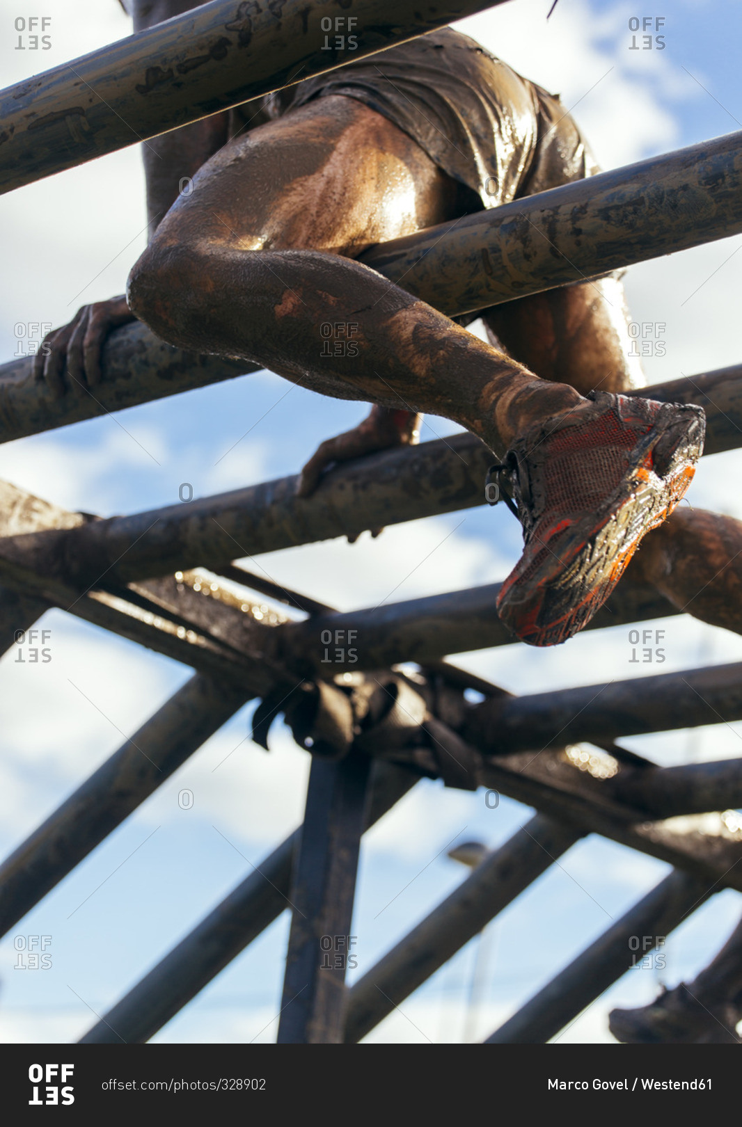 Participants in extreme obstacle race climbing on monkey bars