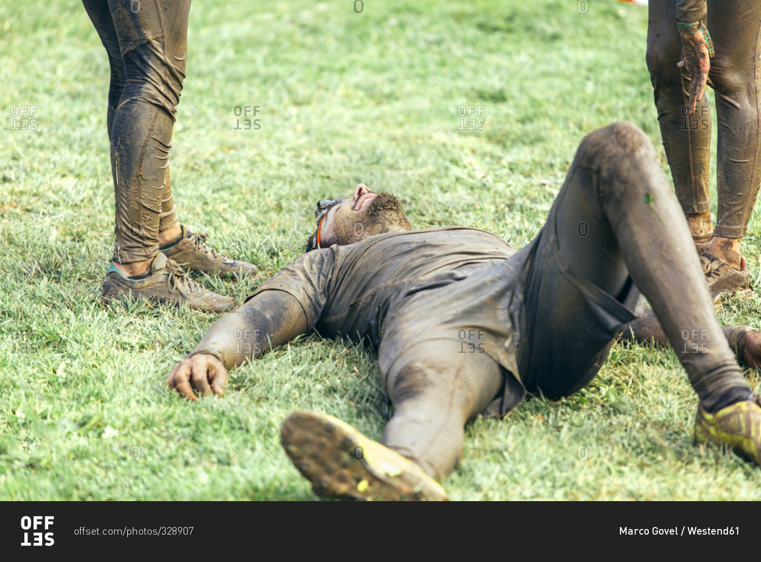 Participant in extreme obstacle race lying exhaustedly on grass