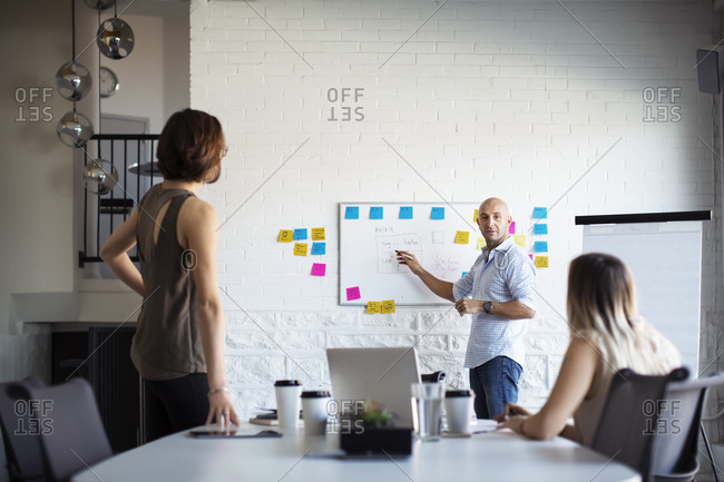 Three colleagues in office brainstorm stock photo - OFFSET