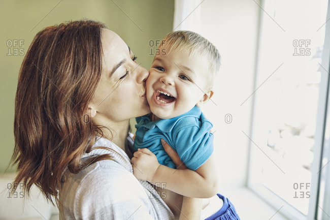 Woman giving little boy kisses on his cheek