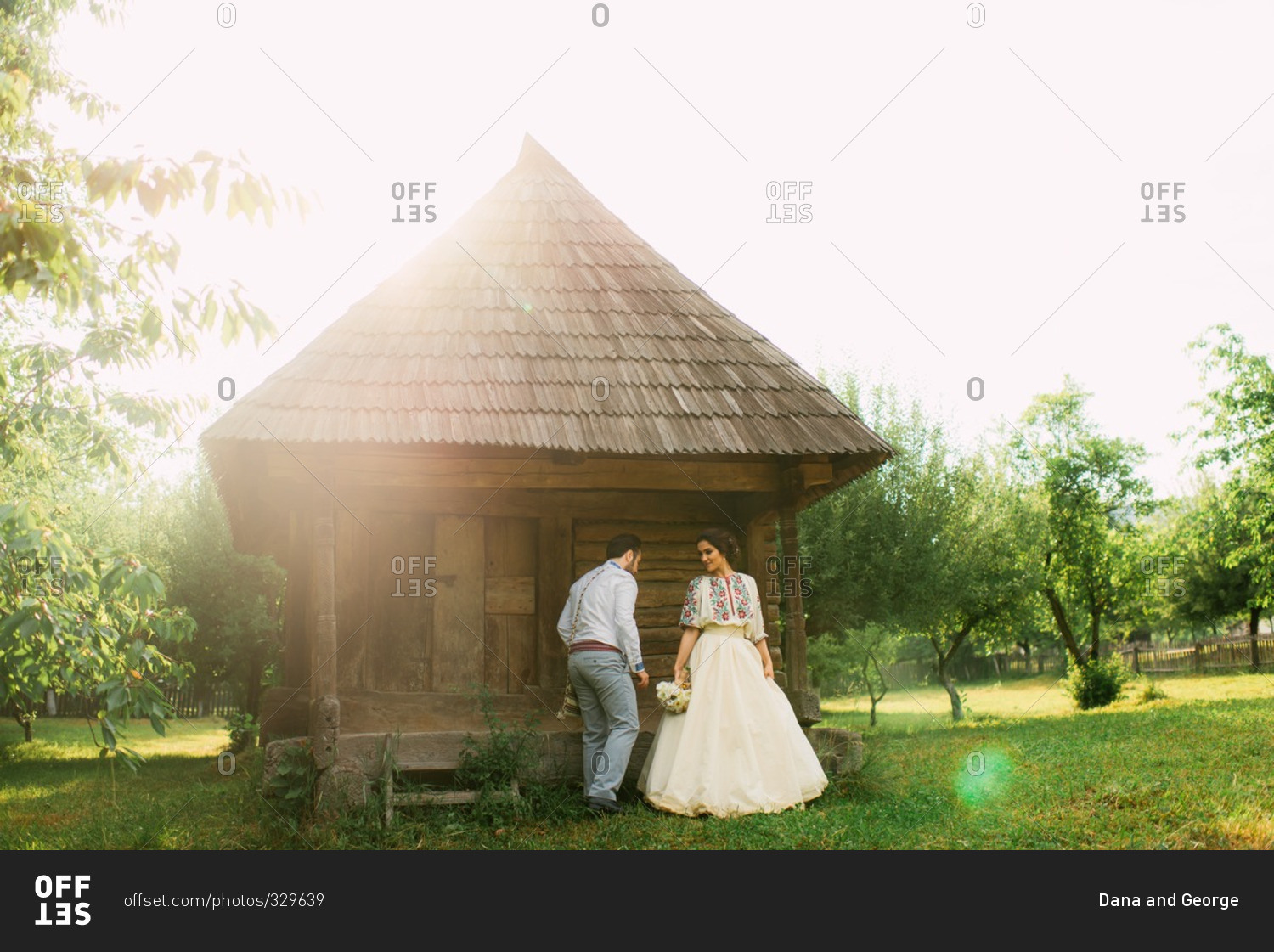 Romanian bride and groom by rustic farm building at a traditional country wedding