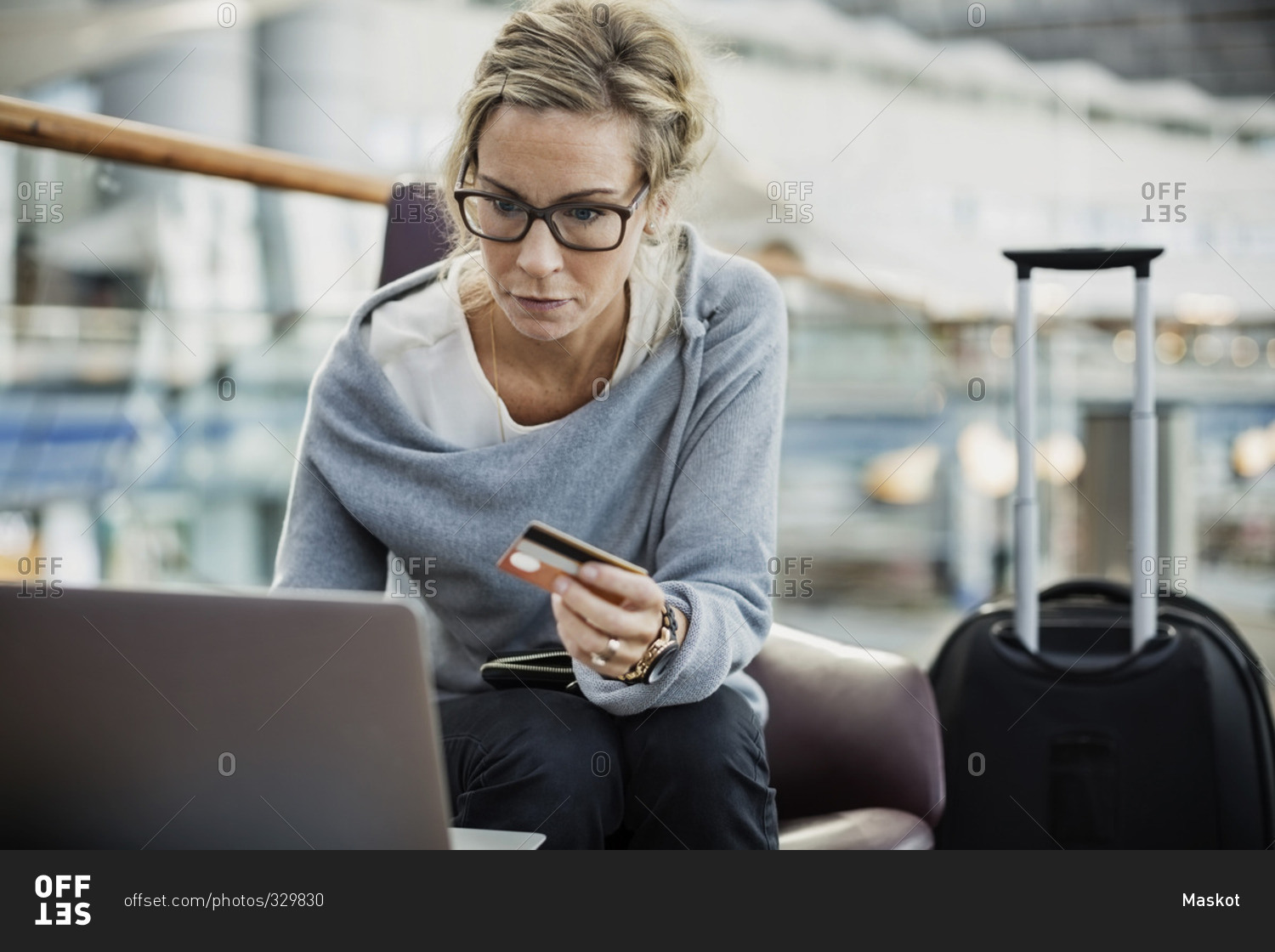 Businesswoman using credit card and laptop at airport lobby
