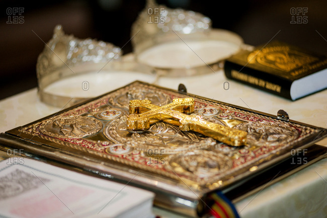 Golden crucifix on closed Bible with silver crowns for religious marriage in the background