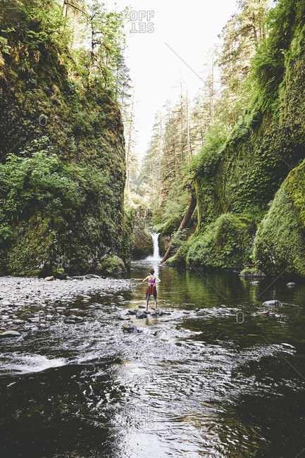 Woman standing in Eagle Creek at the base of Punchbowl Falls, Oregon