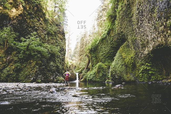 Woman standing in Eagle Creek at the base of Punchbowl Falls, Oregon