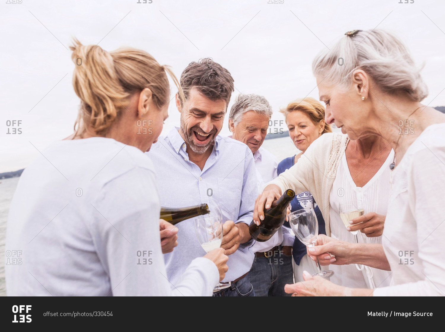 Group of friends pouring wine into wine glasses