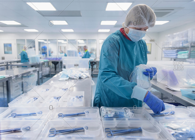 Worker packing surgical instruments in clean room of surgical instruments factory