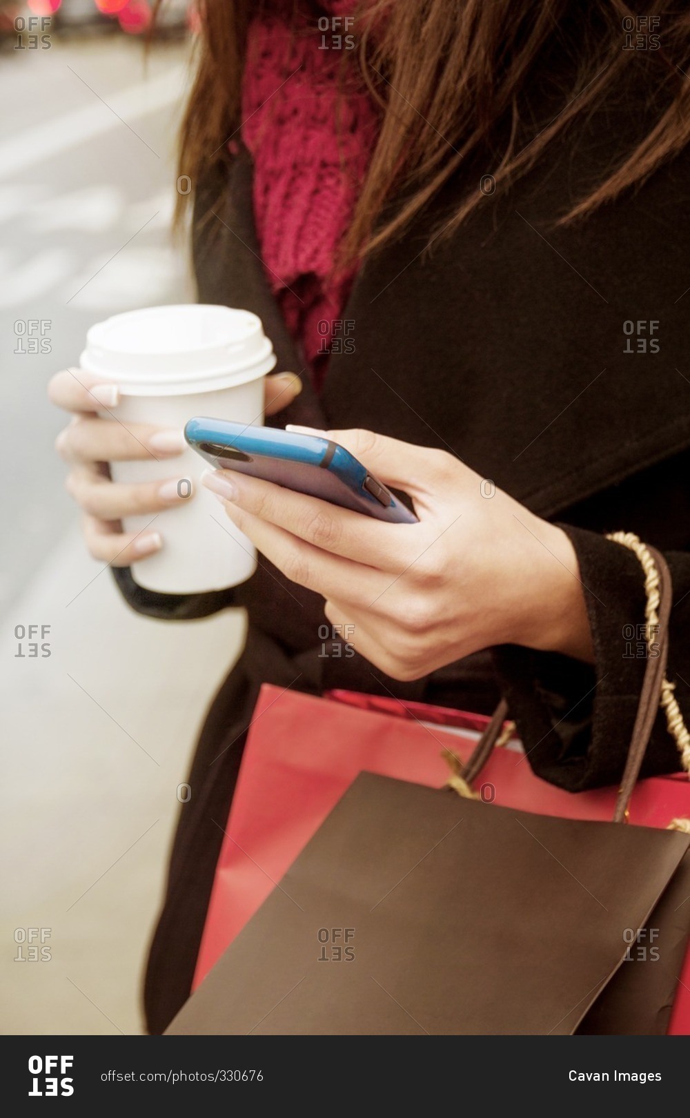Close up of woman using cell phone while drinking coffee on the go