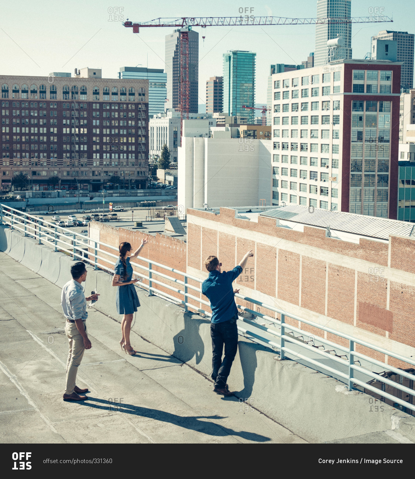 Businesspeople looking and pointing at buildings on roof terrace, Los Angeles, California, USA