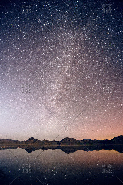 Reflecting pool of mountain range and Milky Way in dramatic night sky, Bonneville, Utah, USA