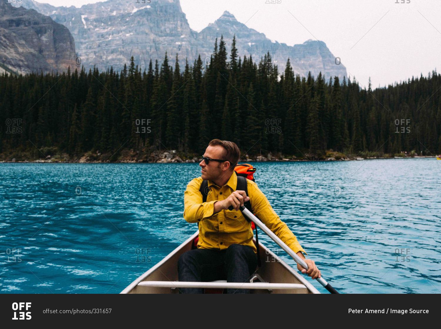Front view of mid adult man paddling canoe, looking away, Moraine lake, Banff National Park, Alberta Canada