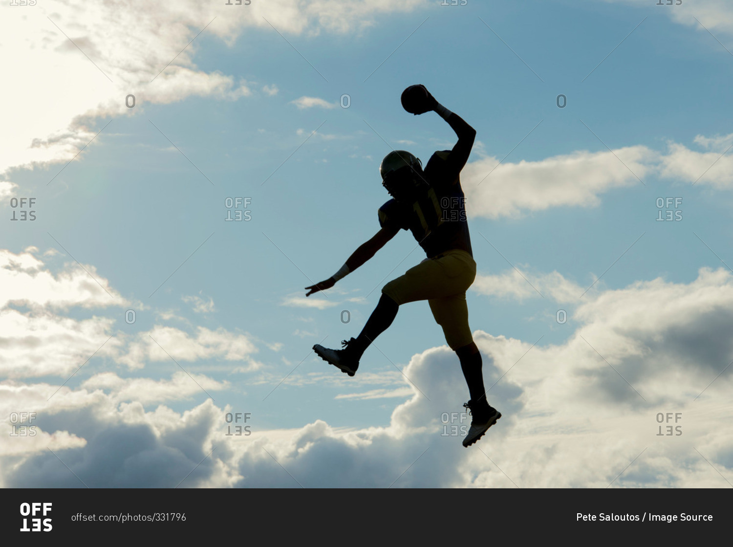 Teenage football player jumping with ball
