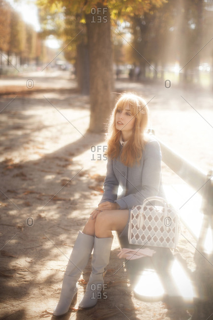 Woman sitting on a city park bench bathed in autumn light