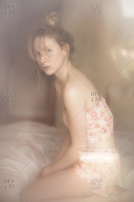 Portrait of a woman kneeling on her bed wearing summer pajamas