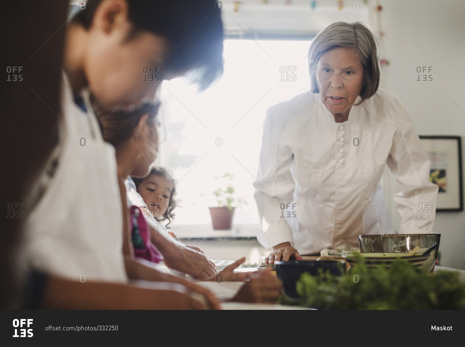 Senior woman guiding family to in making Asian food in kitchen