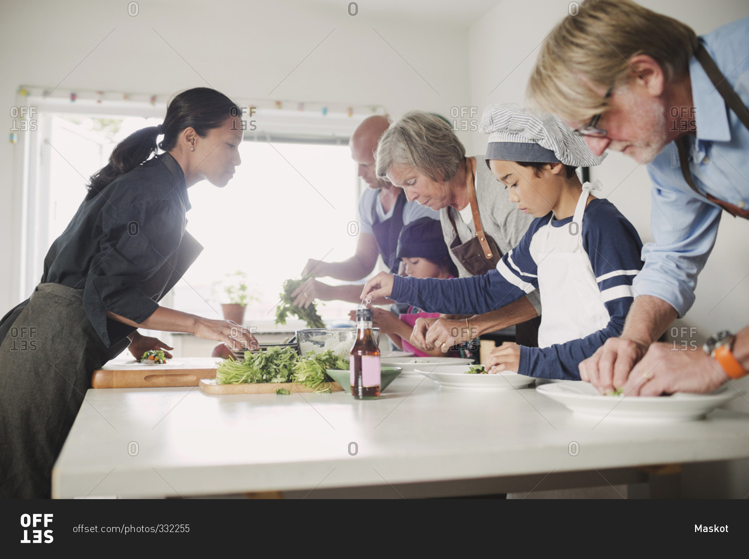 Woman guiding family in preparing Asian food at kitchen