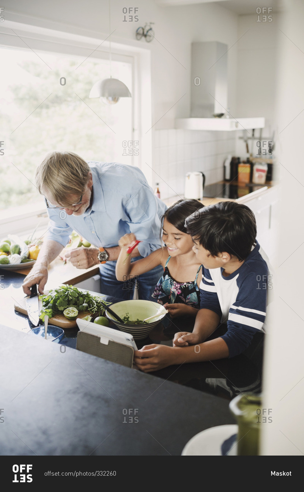 Happy grandfather and children preparing food at kitchen counter