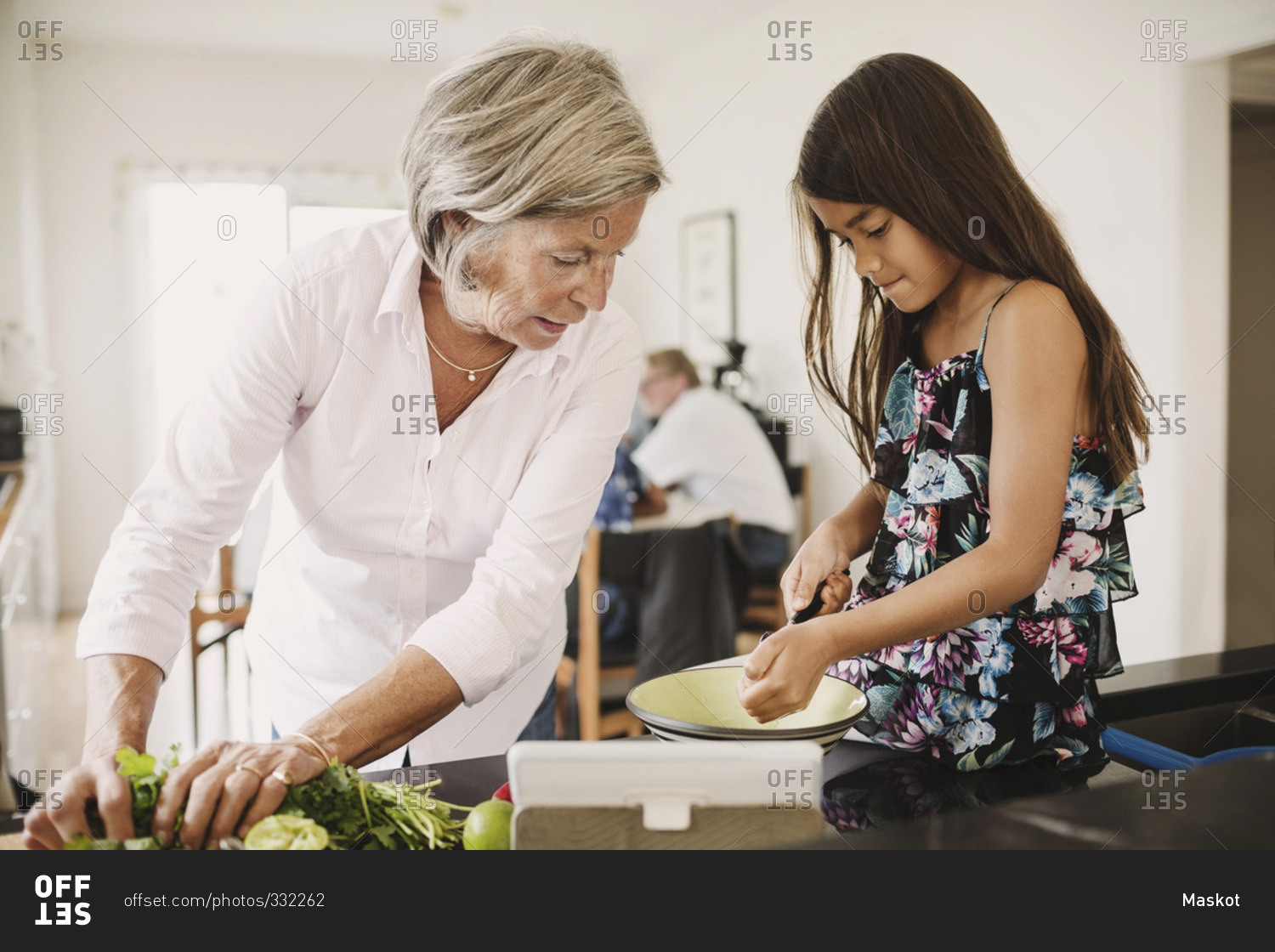 Granddaughter and grandmother preparing food in kitchen