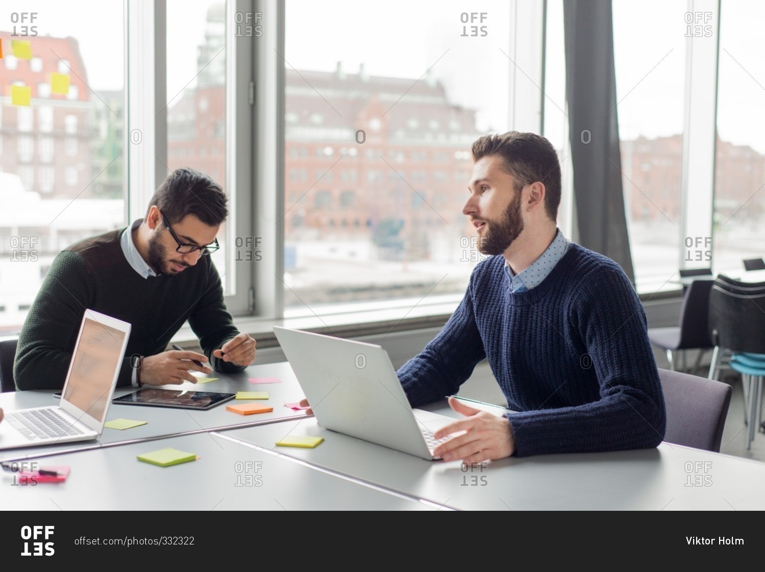 Young men collaborating together at a business meeting stock photo - OFFSET