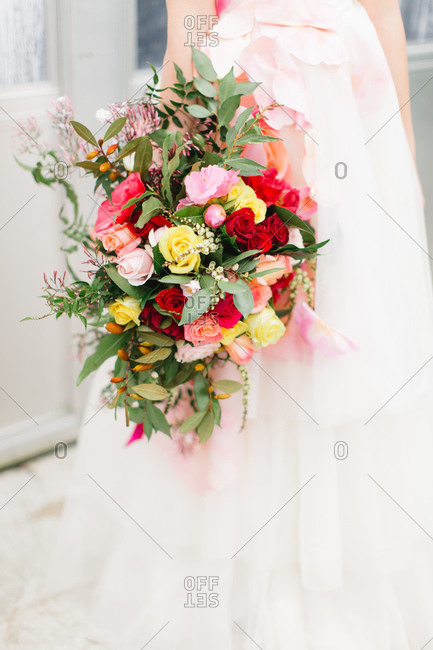 Bride in pink and white, gown holding a colorful bouquet of roses