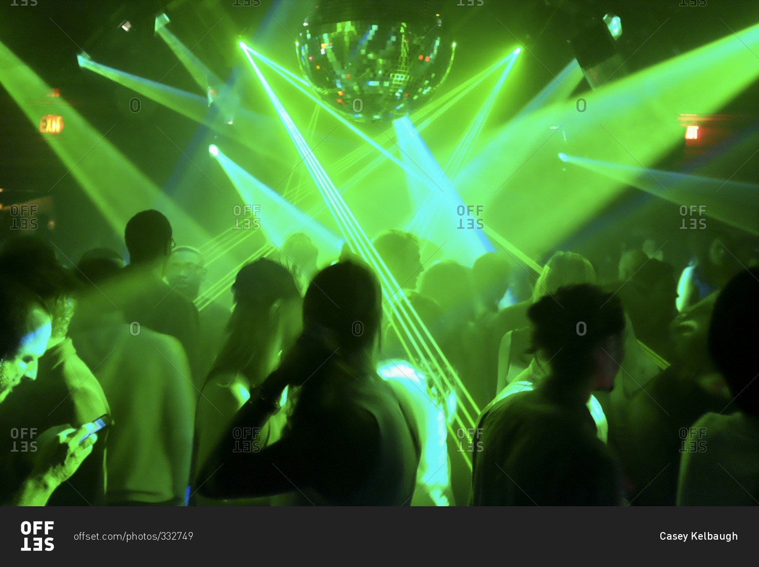 Silhouette of a crowd at a night club with mirror ball and green laser light display