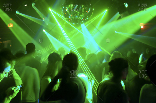 Silhouette of a crowd at a night club with mirror ball and green laser ...