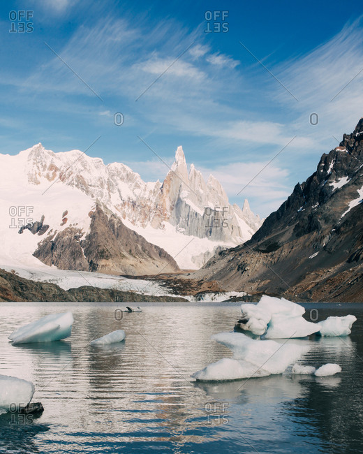 A snow covered mountain peak rising behind a clear glacial lake