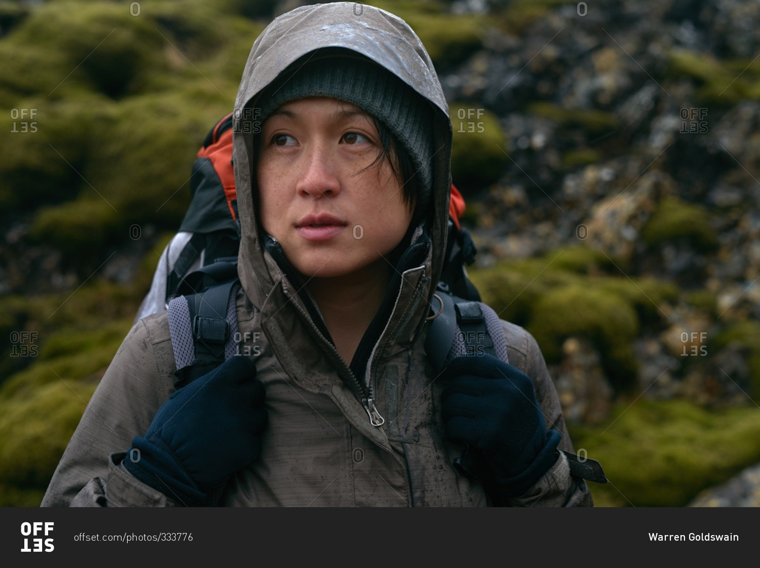 Portrait of an Asian hiker with waterproof gear and backpack in the rain while trekking on an adventure expedition in Iceland
