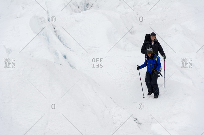 Hikers on the frozen and barren wasteland of folded ice on the surface of the Greenland Ice Sheet