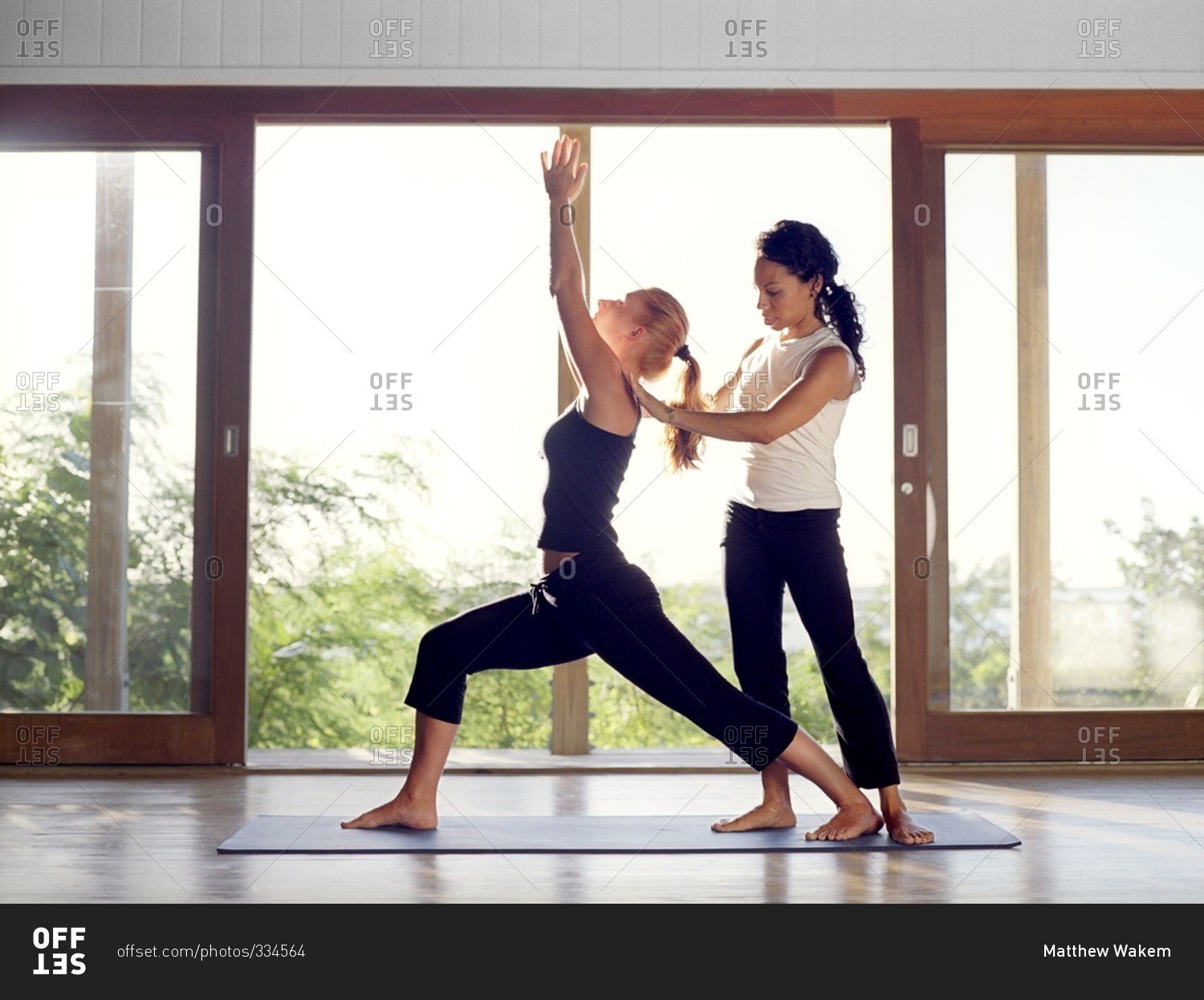Yoga instructor helping a student with warrior pose during a yoga class