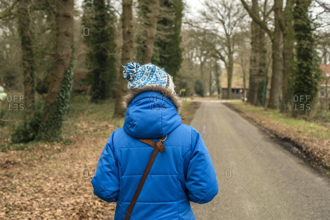 Woman with woolen cap walking on rural road