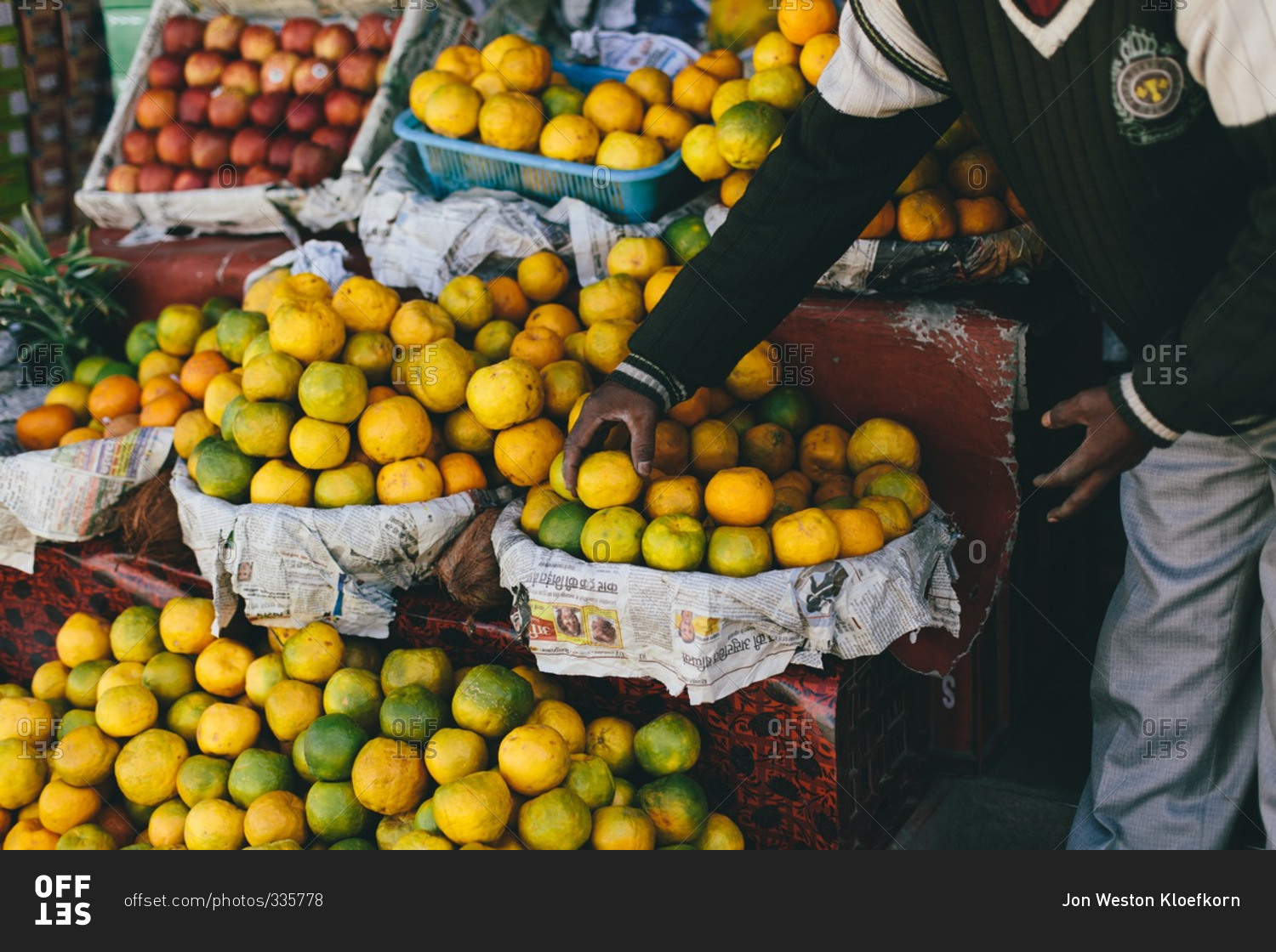 Man picking citrus fruit from a fruit stand in India
