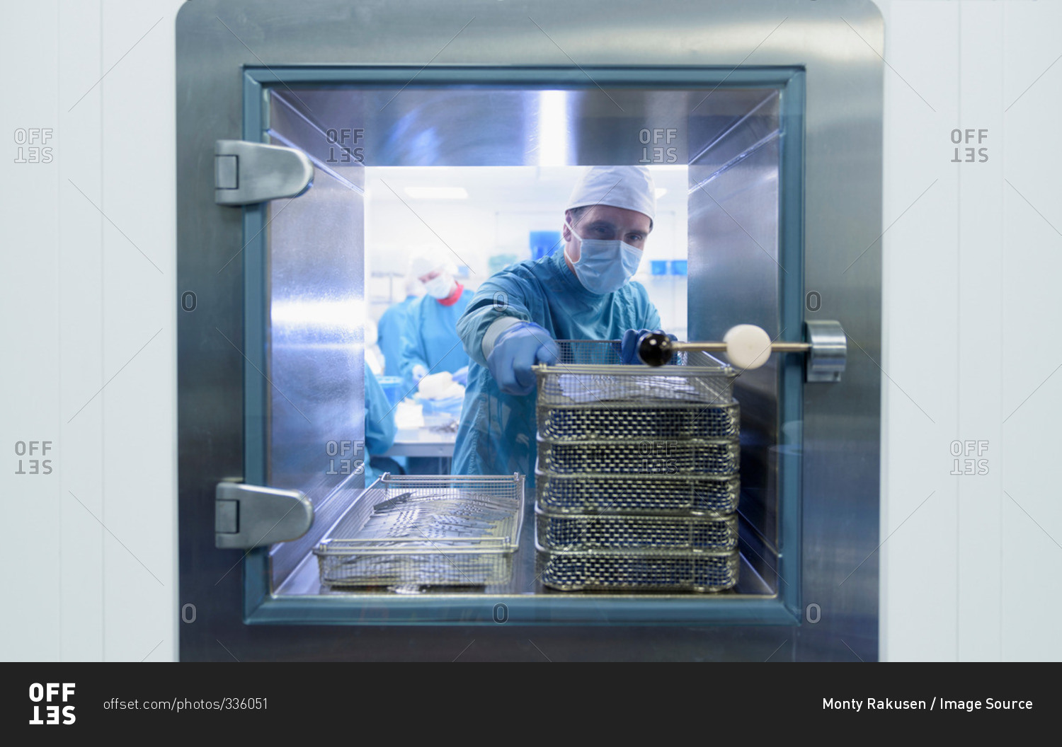 Worker putting surgical instruments into air lock in clean room of surgical instruments factory