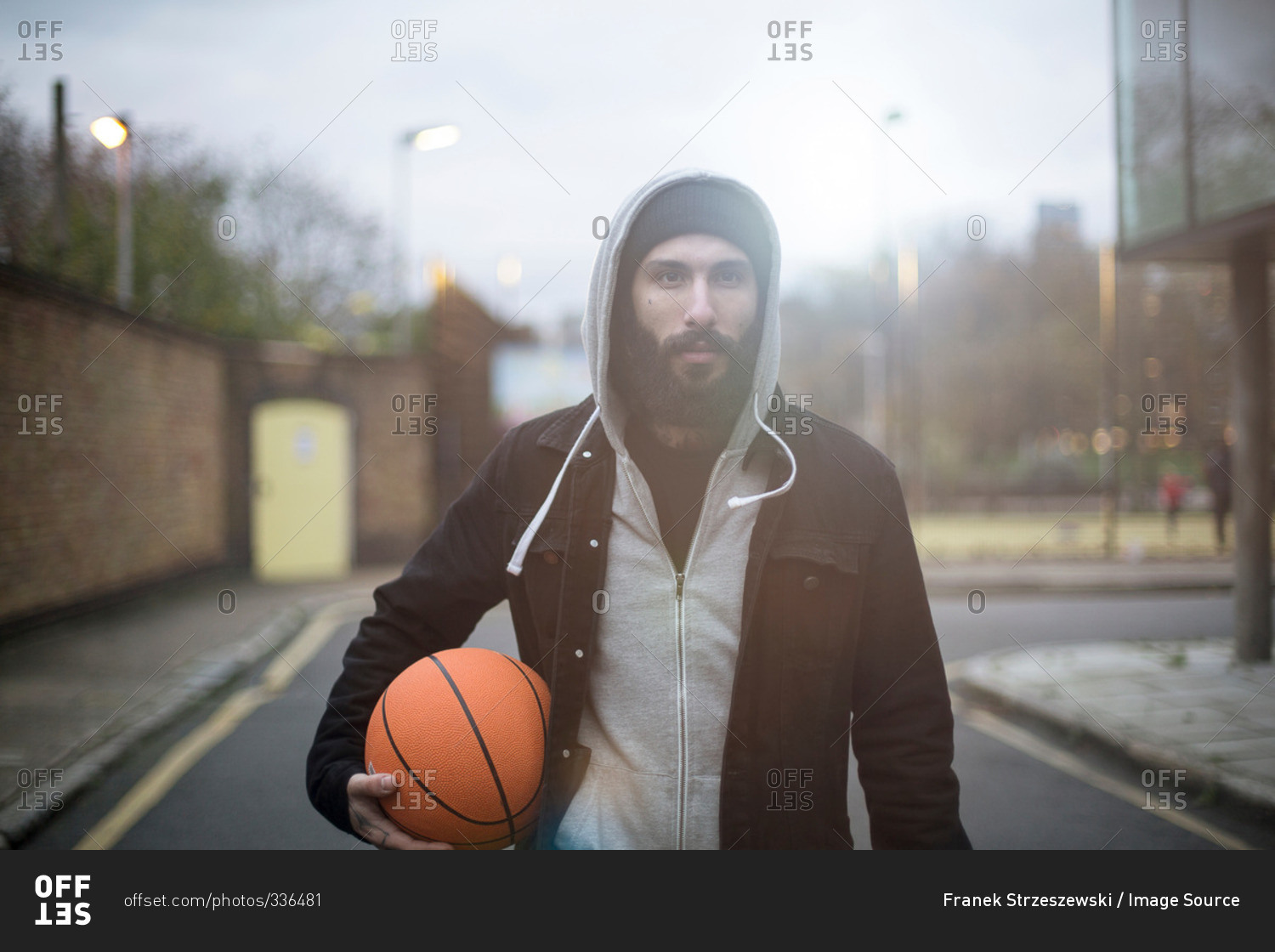 Portrait of mid adult man in street, holding basketball