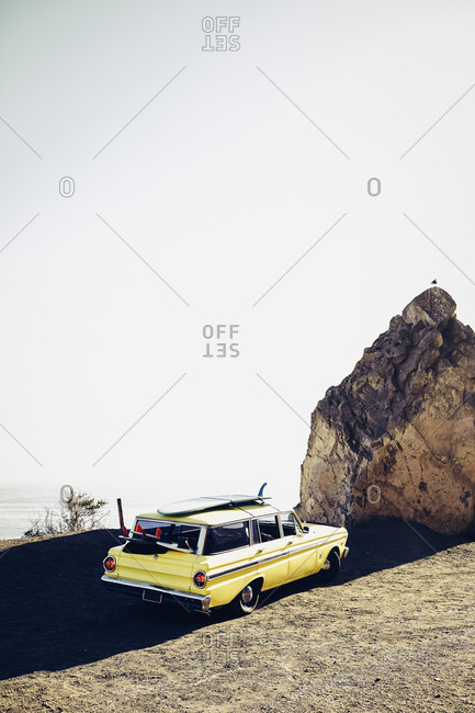 Vintage station wagon with skateboard on roof parked at beach