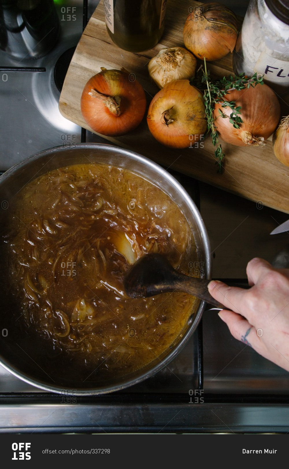 Hand stirring French onion soup in a sauce pan