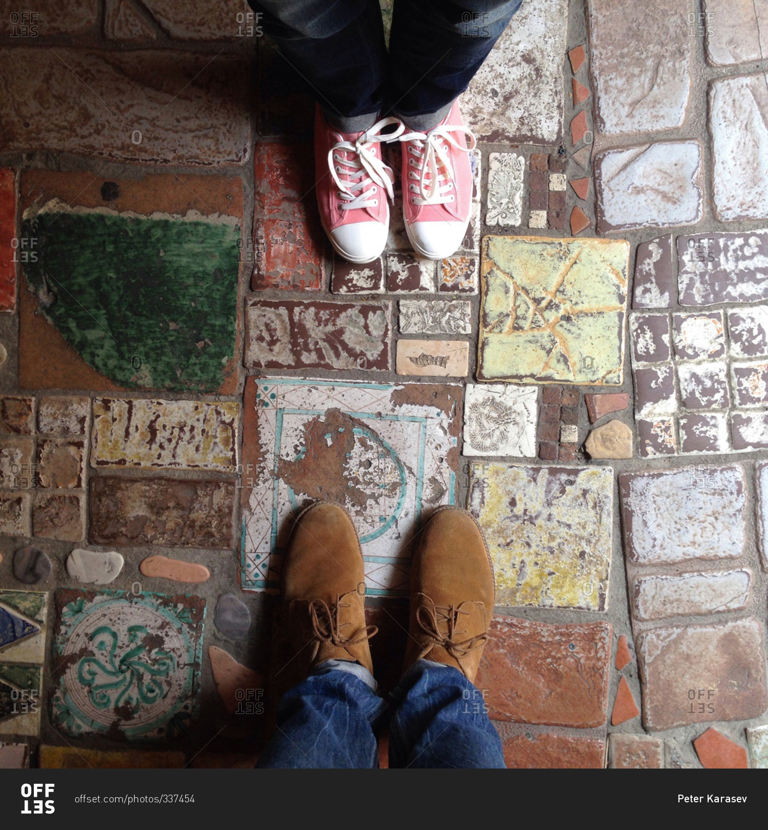 Overhead view of two pairs of shoes on a colorful tile floor