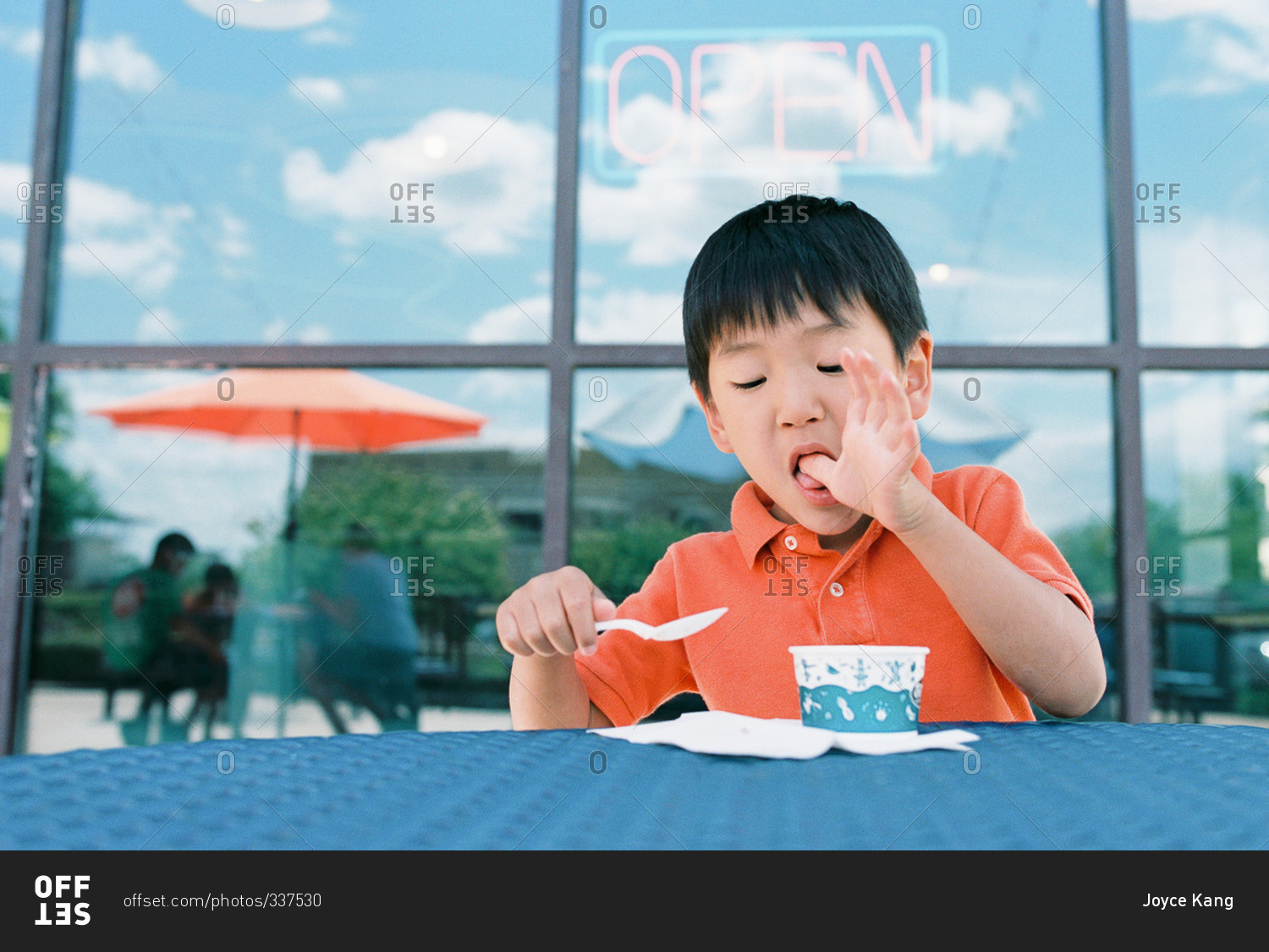 Little boy eating ice cream and licking his fingers