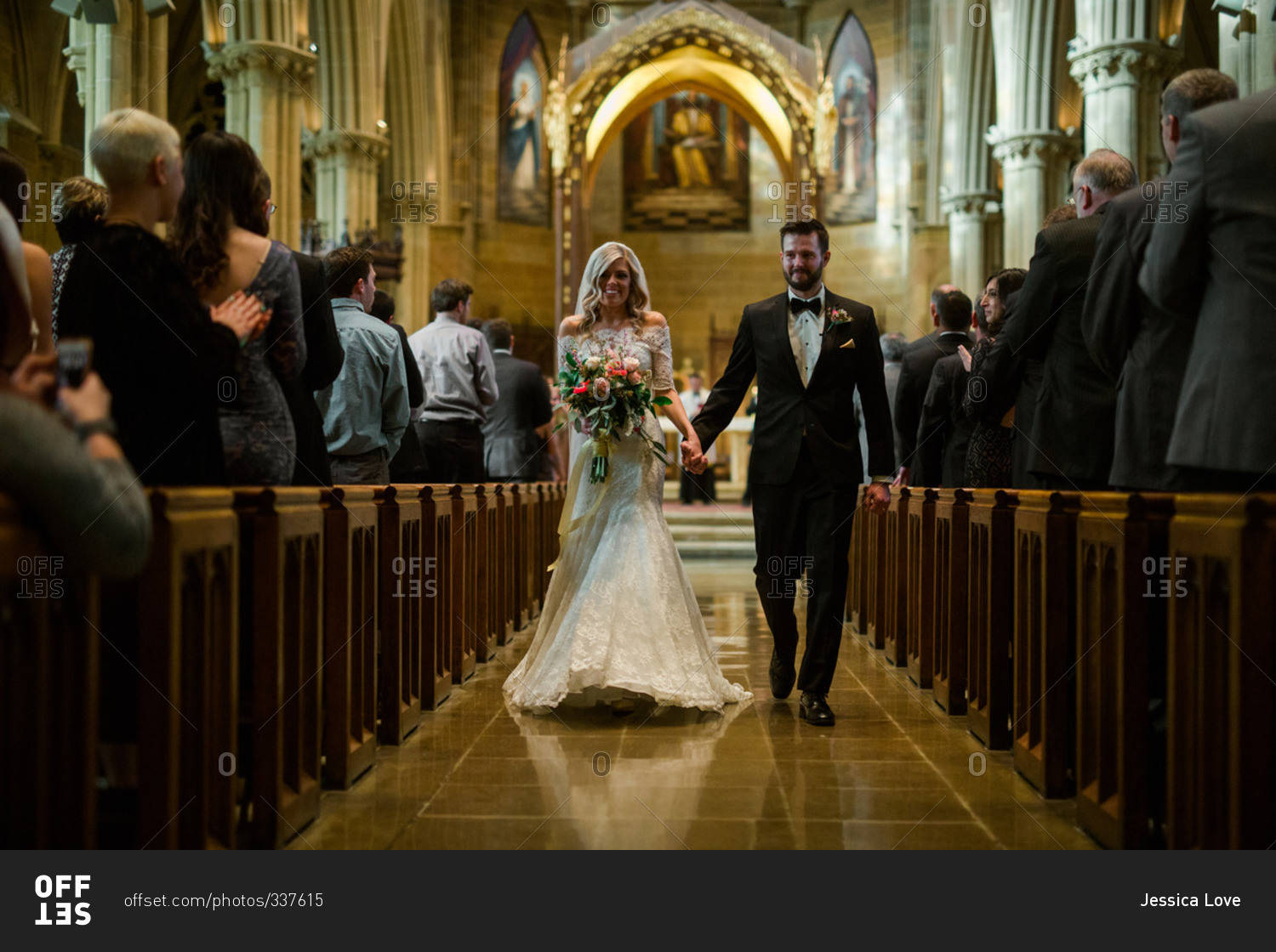 Bride and groom walk down church aisle holding hands
