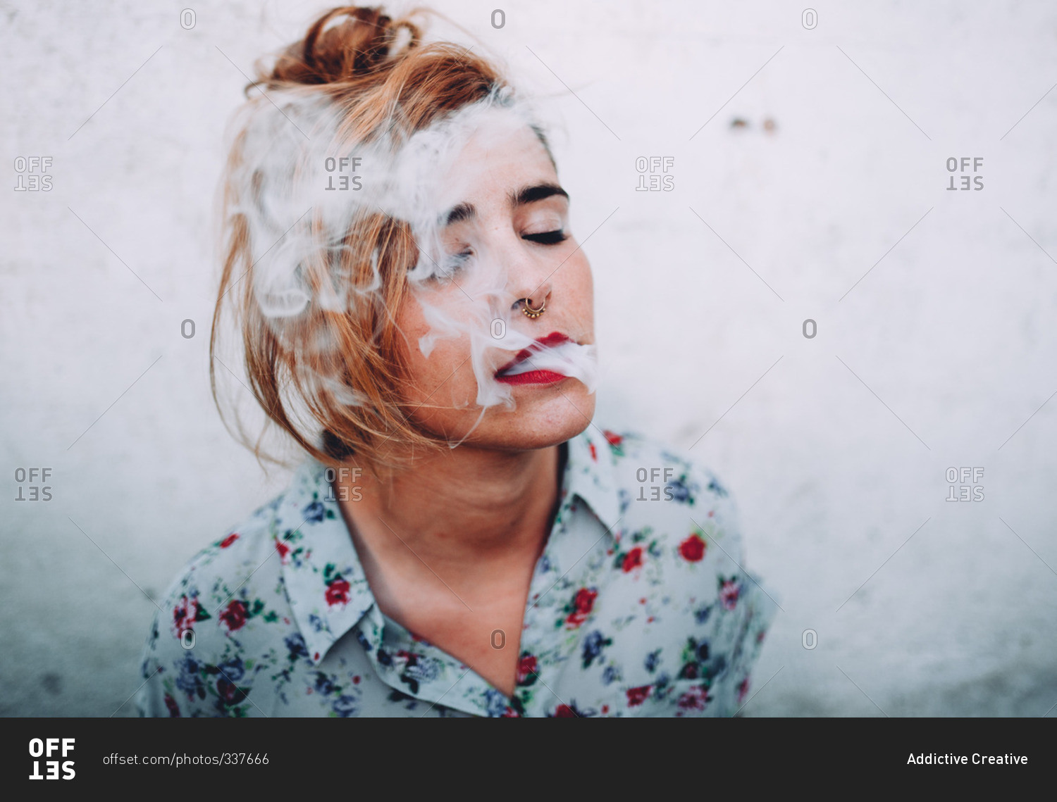 Woman with nose piercings exhaling cigarette smoke with her eyes closed