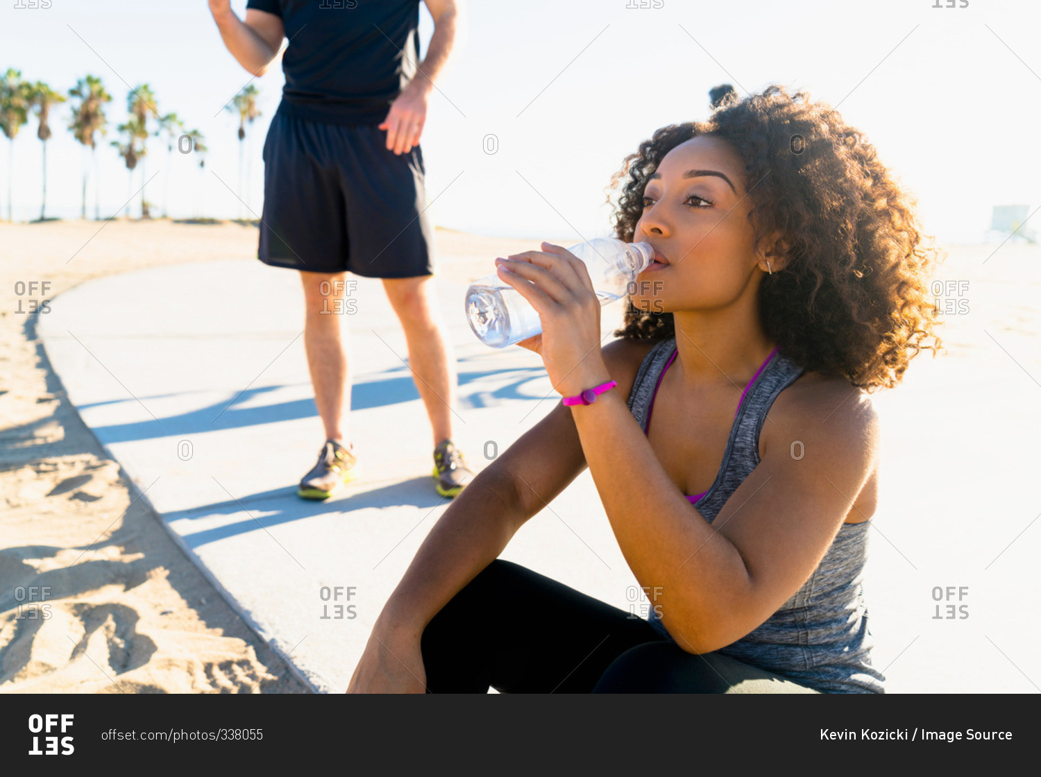 Mid adult woman, by beach, drinking from water bottle stock photo - OFFSET