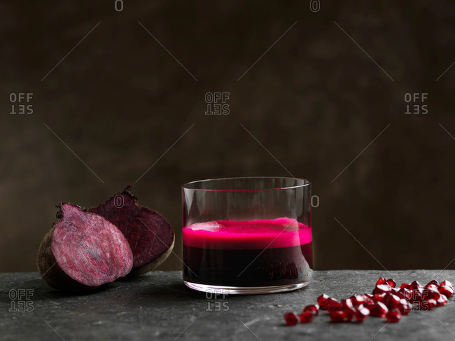 Purple raw beetroot and apple juice, halved beetroot and pomegranate seeds