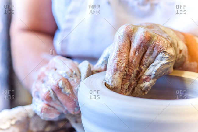 Close up of hands of female potter making pot on potters wheel