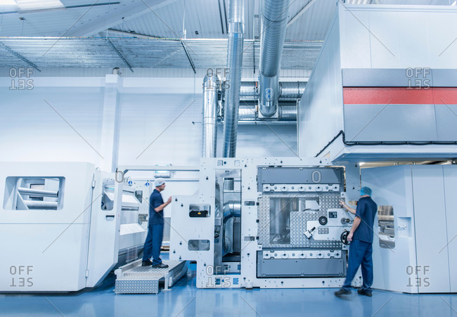 Workers operating printing machine in food packaging printing factory