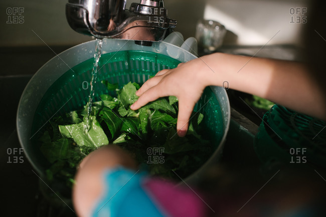 Girl rinsing veggies in a sink