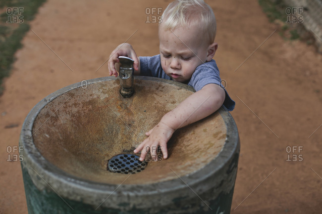 Little boy playing with outdoor drinking fountain