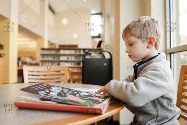 Boy reading at library table