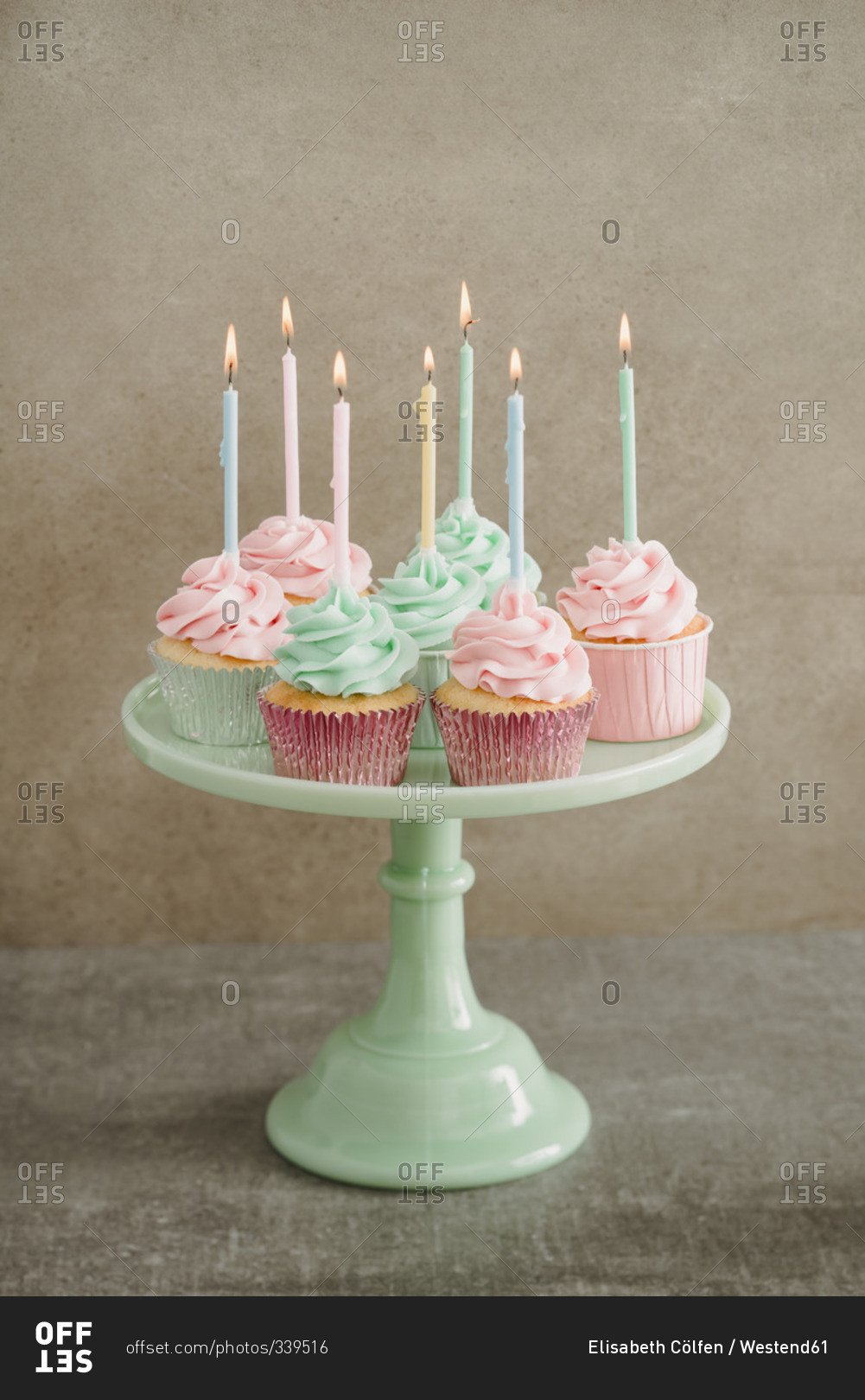Cup cakes with lighted candles on a cake stand