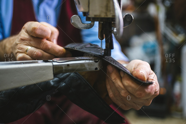 Shoemaker sewing a shoe with machine in his workshop, close-up